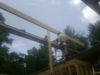 Carpenter setting a ridge beam over a new addition frame in Sharpsburg