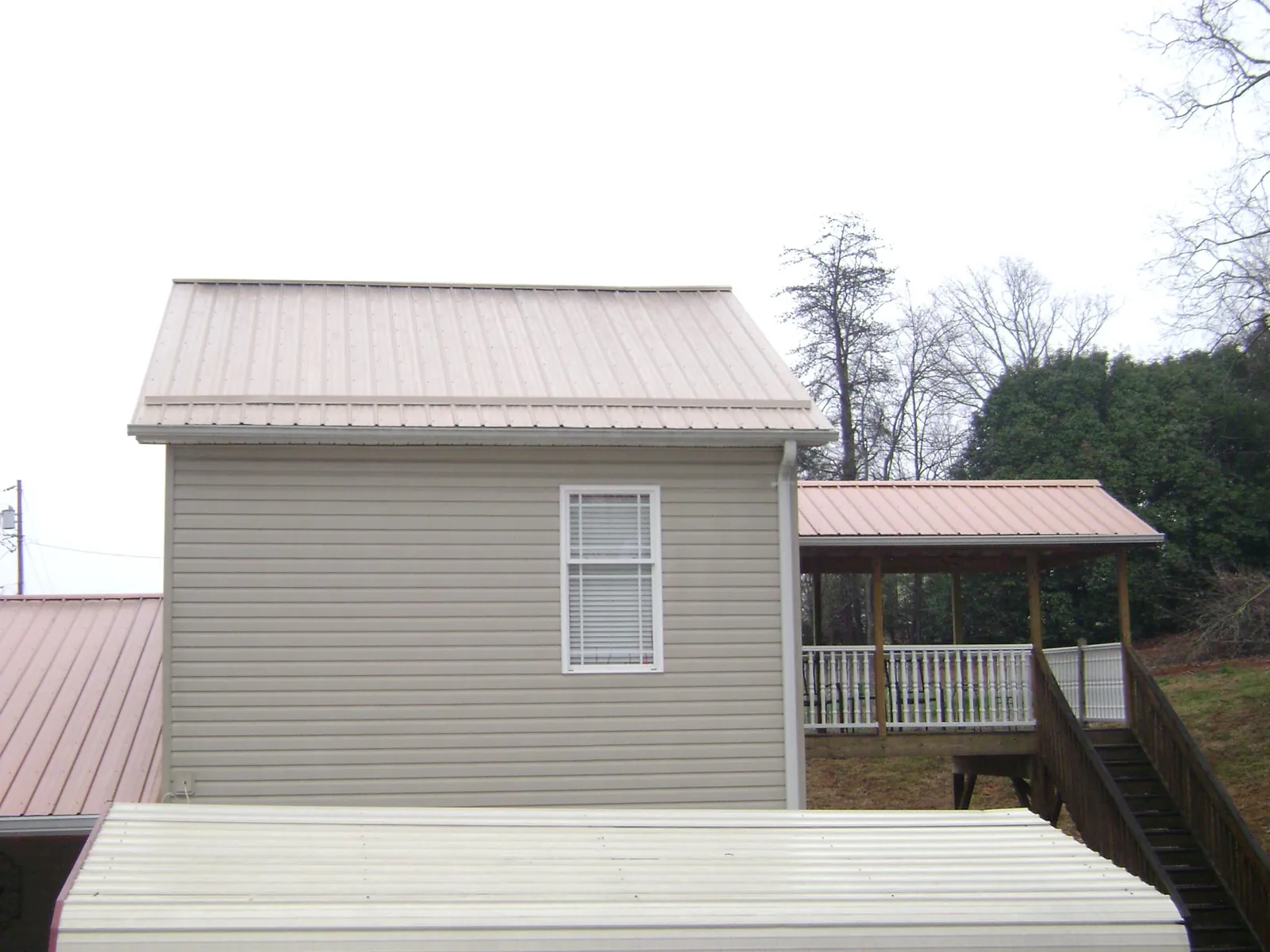 Tan metal roofs on a two story addition and attached porch, from a Roof Replacement job in Sharpsburg