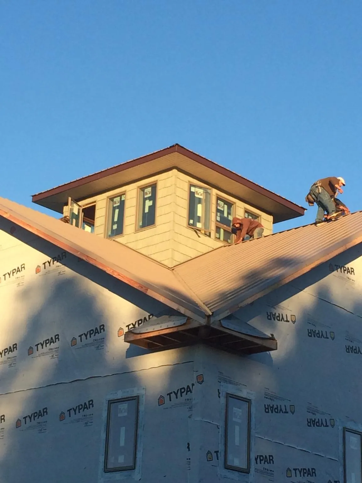 Roofers working around a rooftop cupola on a new metal roof at sunset — Roof Waterproofing in Sharpsburg by Roofing Brothers